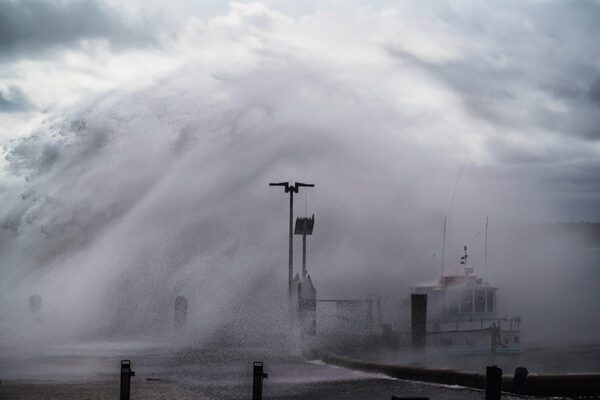 Large wave crashing into Mornington Pier on stormy day